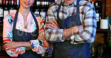 酒吧服务员和酒吧服务员站在酒吧柜台交叉双臂的画像